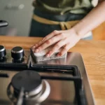Hand cleaning stove with sponge. Image for article on maintaining household appliances.